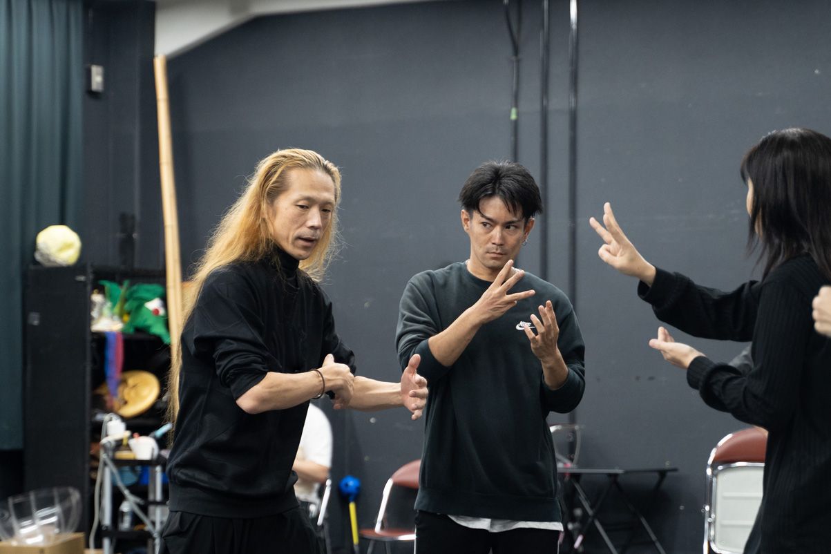 動きを確認している二人の写真。端に、手話通訳の後ろ姿も写り込んでいる。