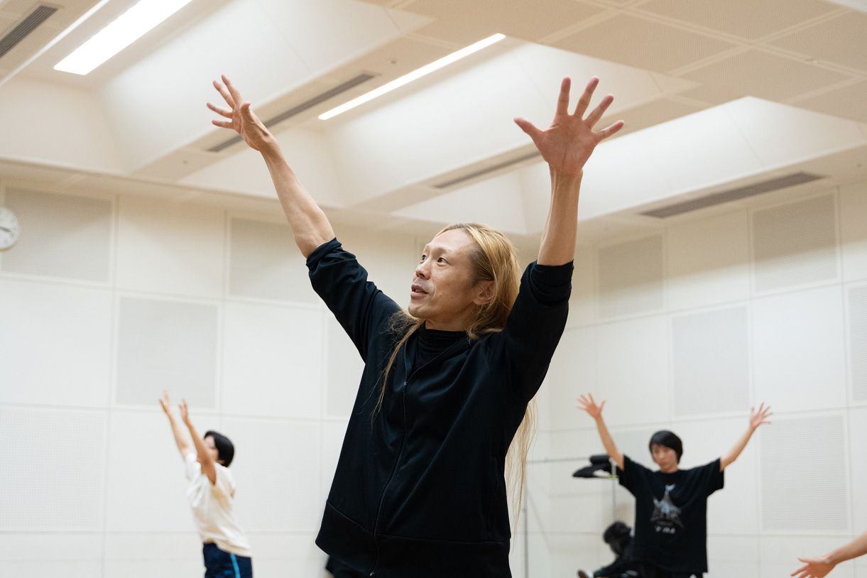 両手を広げて踊る上半身の写真。