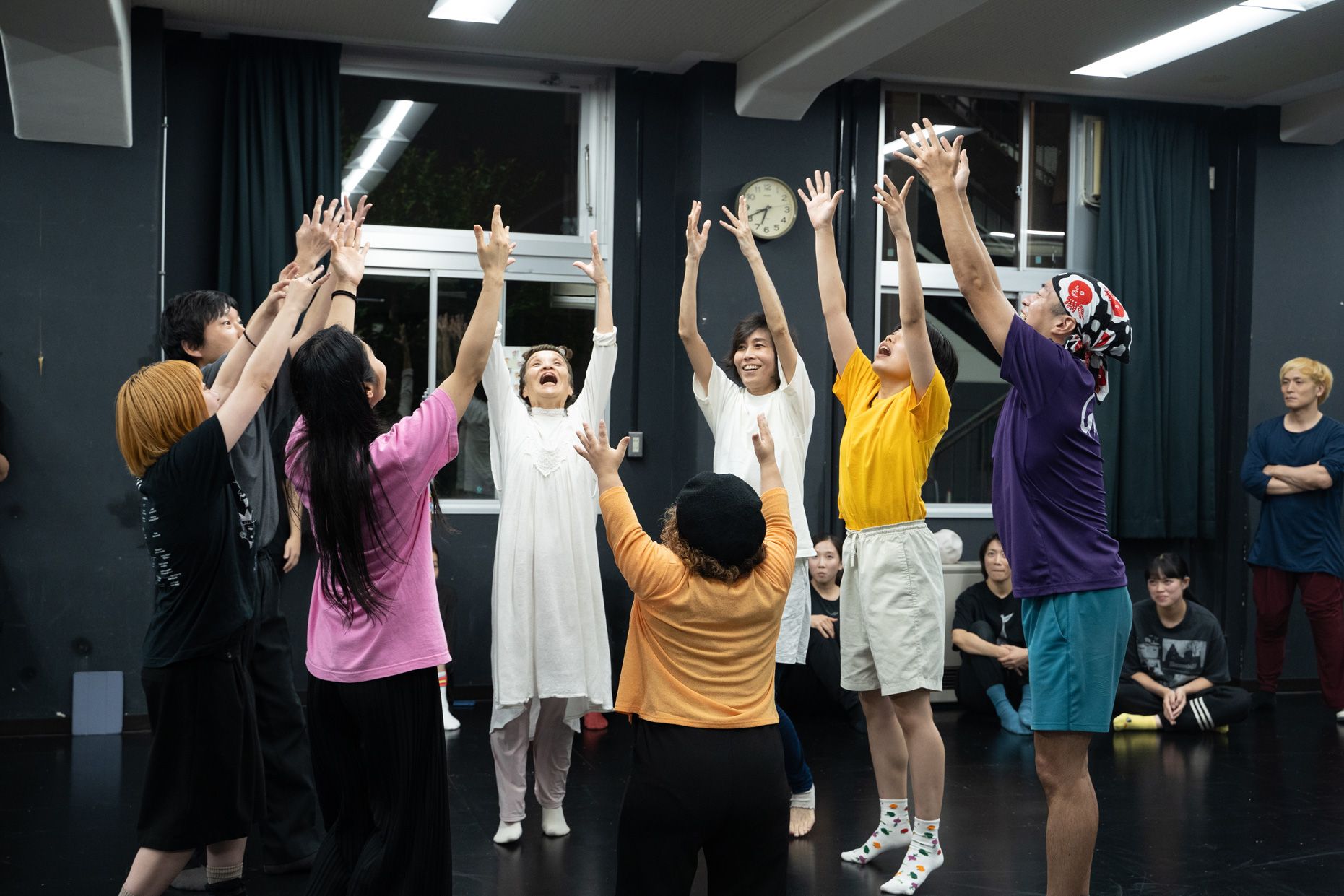 8人が輪になり、それぞれ両手を垂直に高くあげている